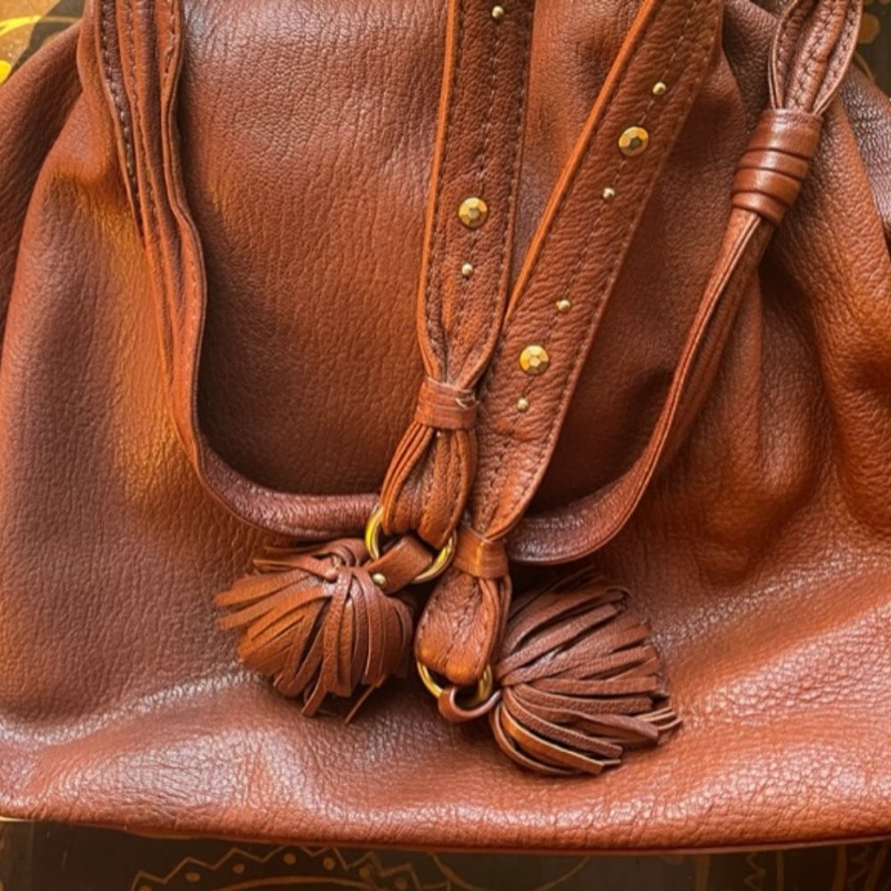 This is a Sigrid Olsen leather purse with tassles and goldtone hardware.